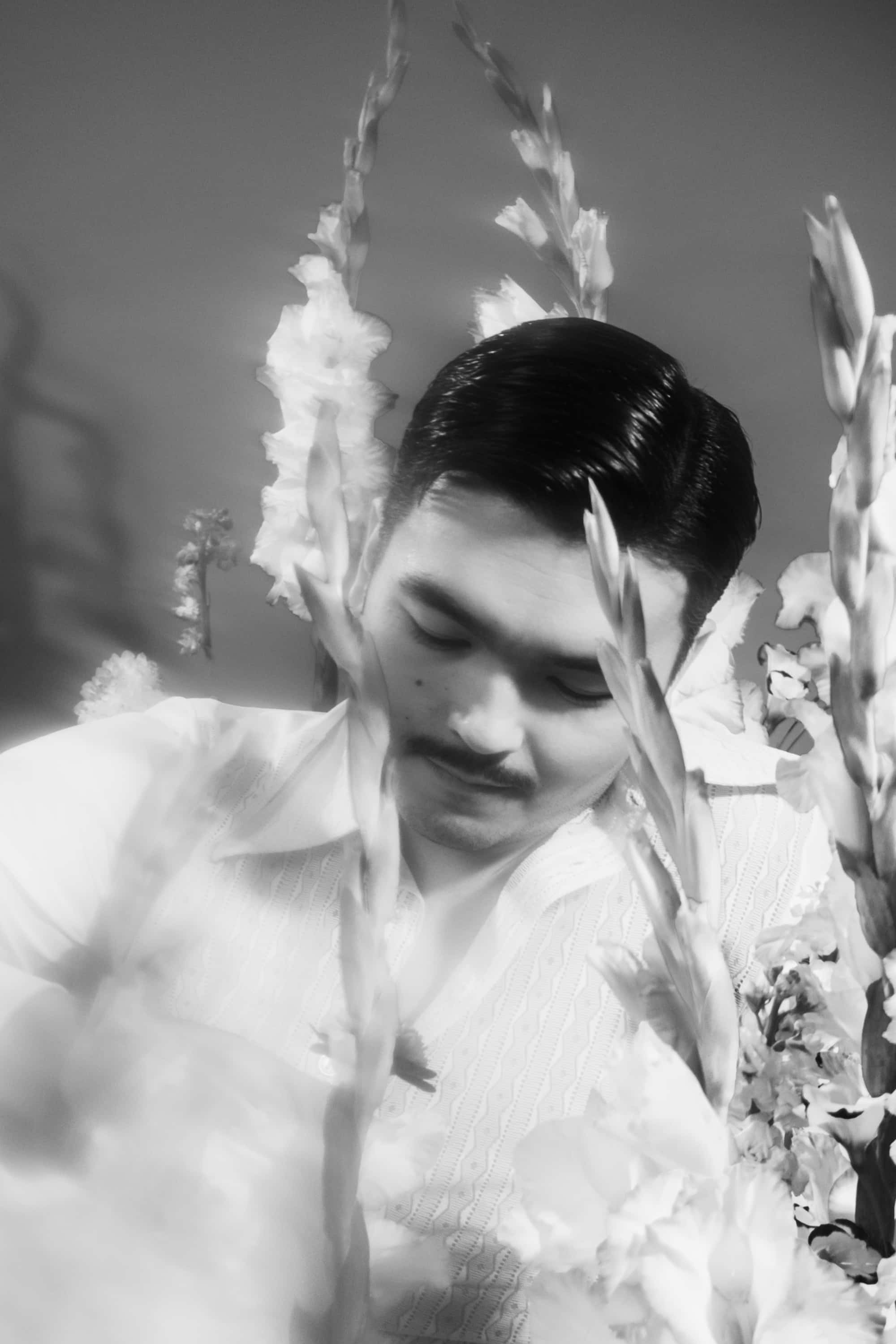Black-and-white portrait of Almás among white gladioli