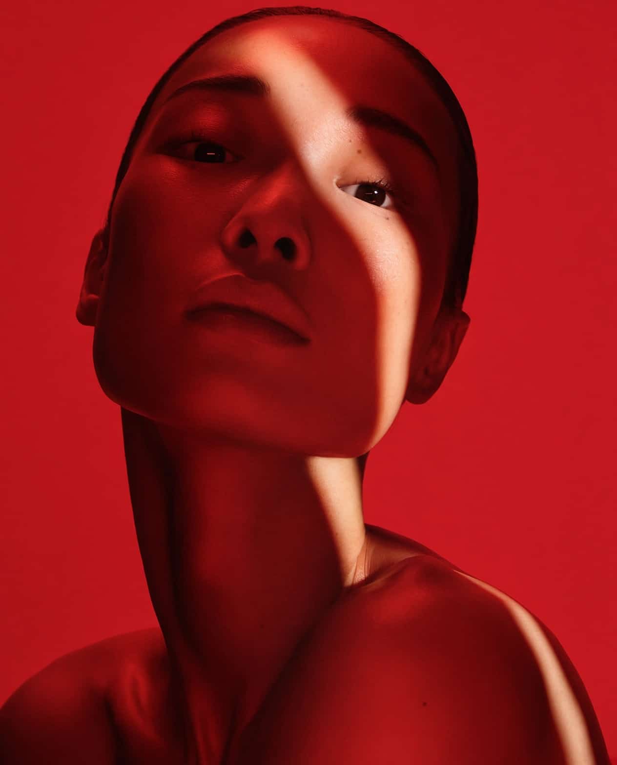 Portrait of BIBI under deep red light, a shaft of daylight across her face