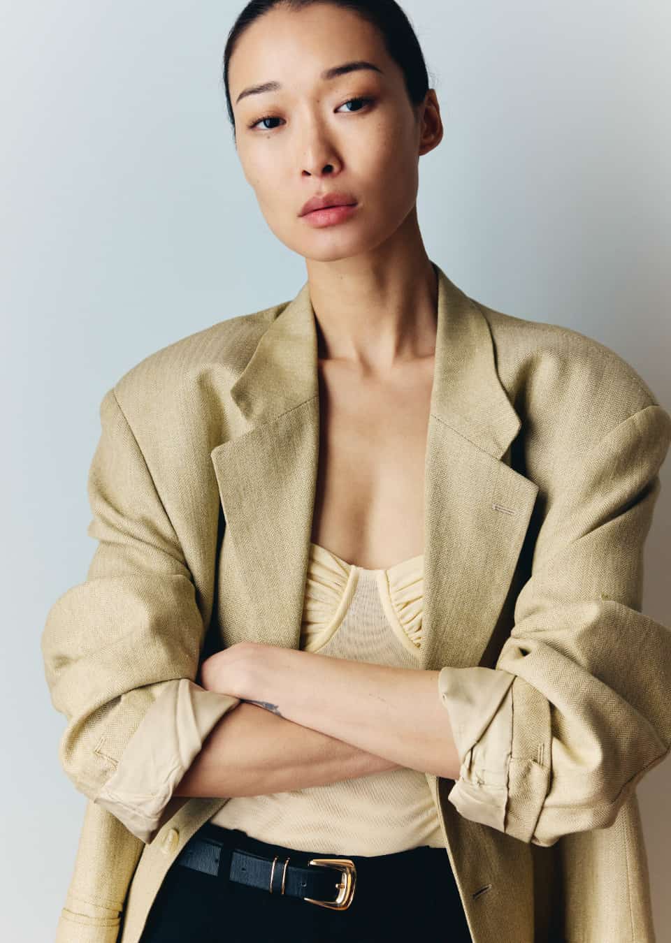 BIBI in an oversized beige linen blazer, arms crossed