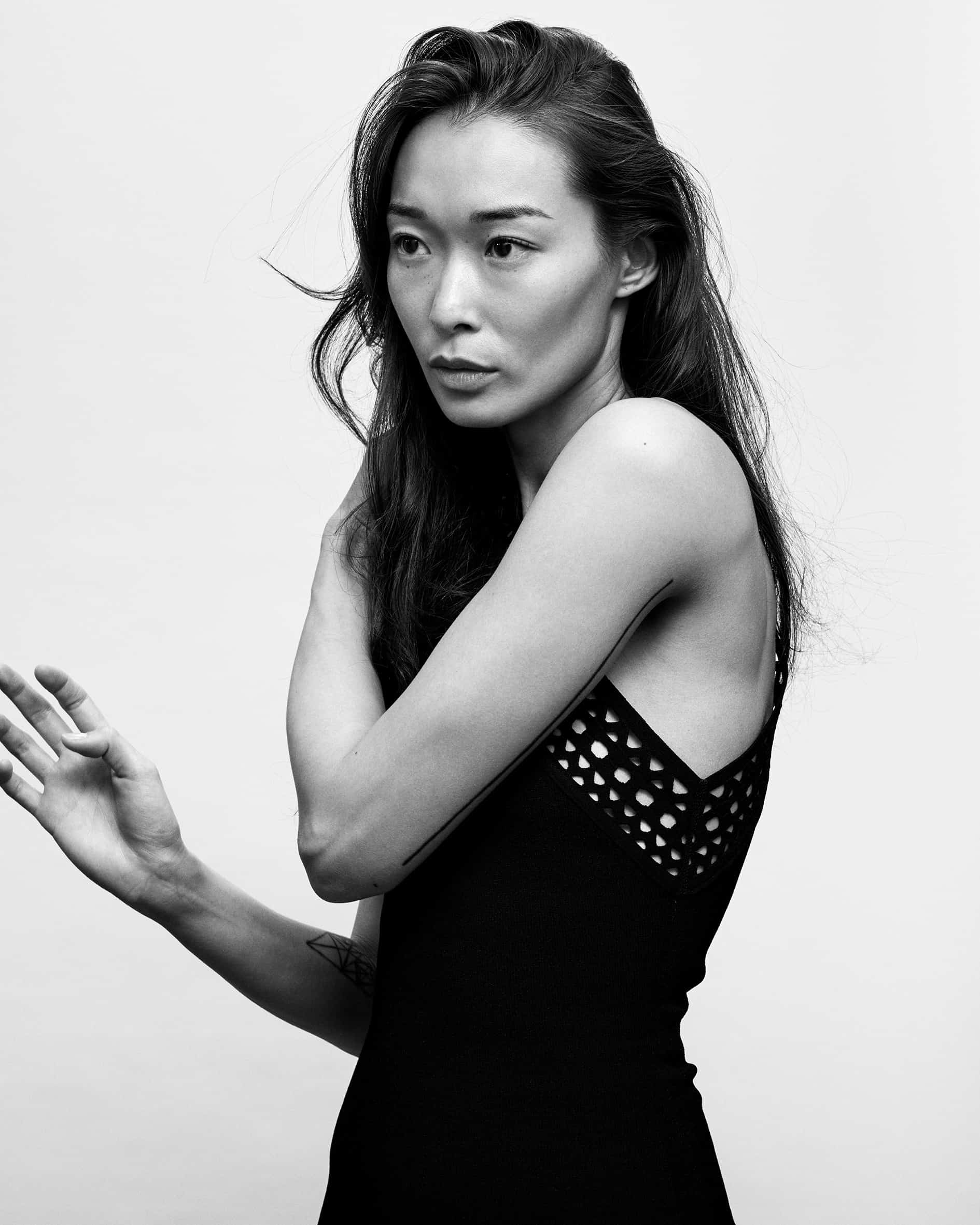 Black-and-white side portrait of BIBI in a black open-knit dress